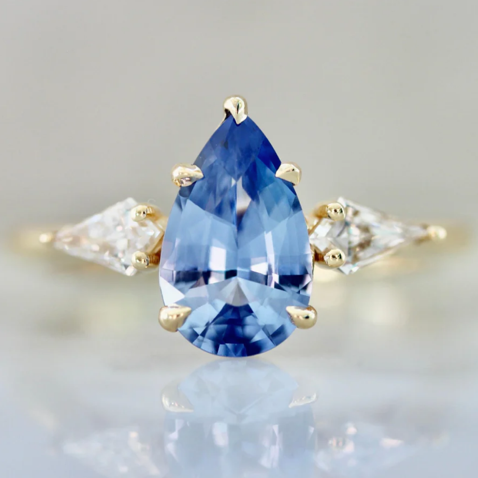 Pear cut cornflower blue sapphire engagement ring with kite cut side stones by Gem Breakfast
