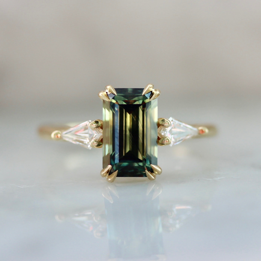Moody emerald cut bi-color green sapphire custom engagement ring with kite side diamonds by Gem Breakfast