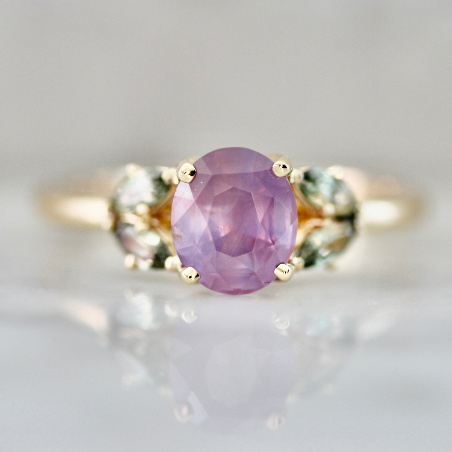 Nature inspired engagement ring with oval cut opalescent purple sapphire and green sapphire accents in a custom setting by Gem Breakfast