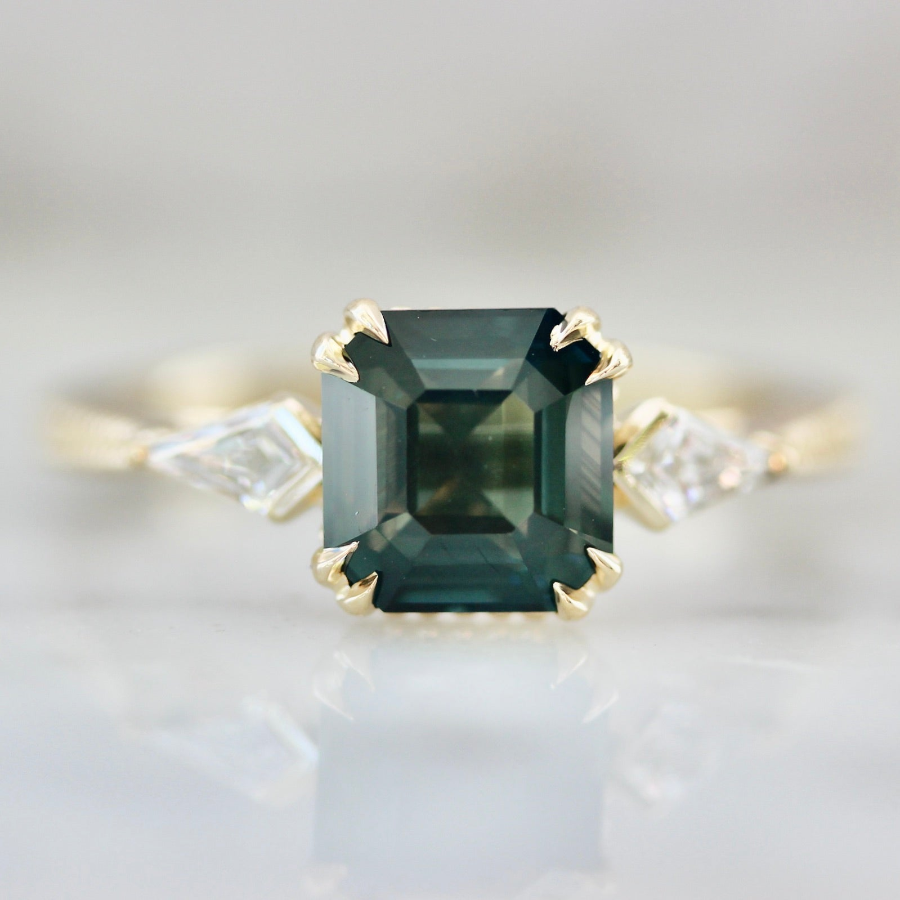 Custom engagement ring with green Asscher cut sapphire and Kite Diamond side stones by Gem Breakfast
