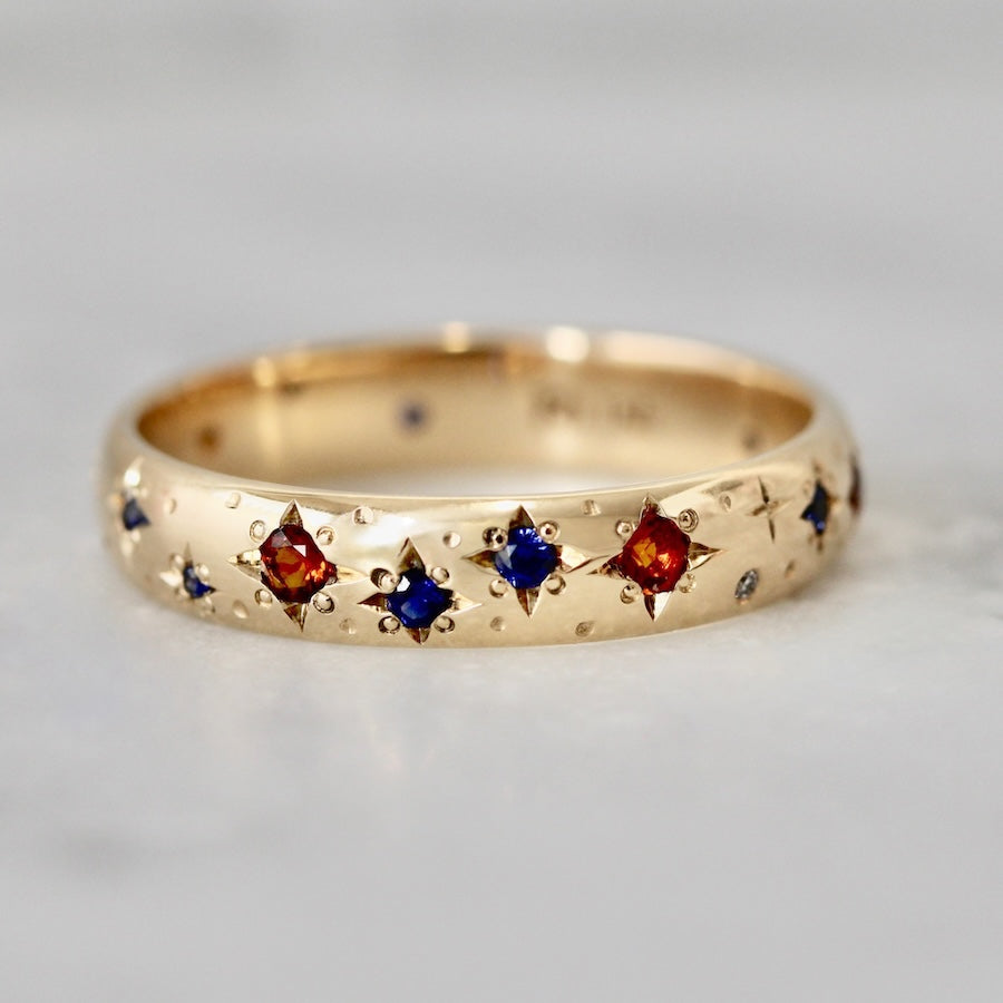 Thick 14k yellow gold custom wedding band with hand-engraved stars and star-set rubies and sapphires by Gem Breakfast