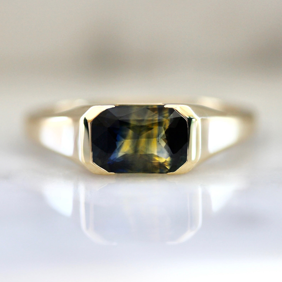 Custom engagement ring with green bi-color sapphire in a partial bezel setting by Gem Breakfast