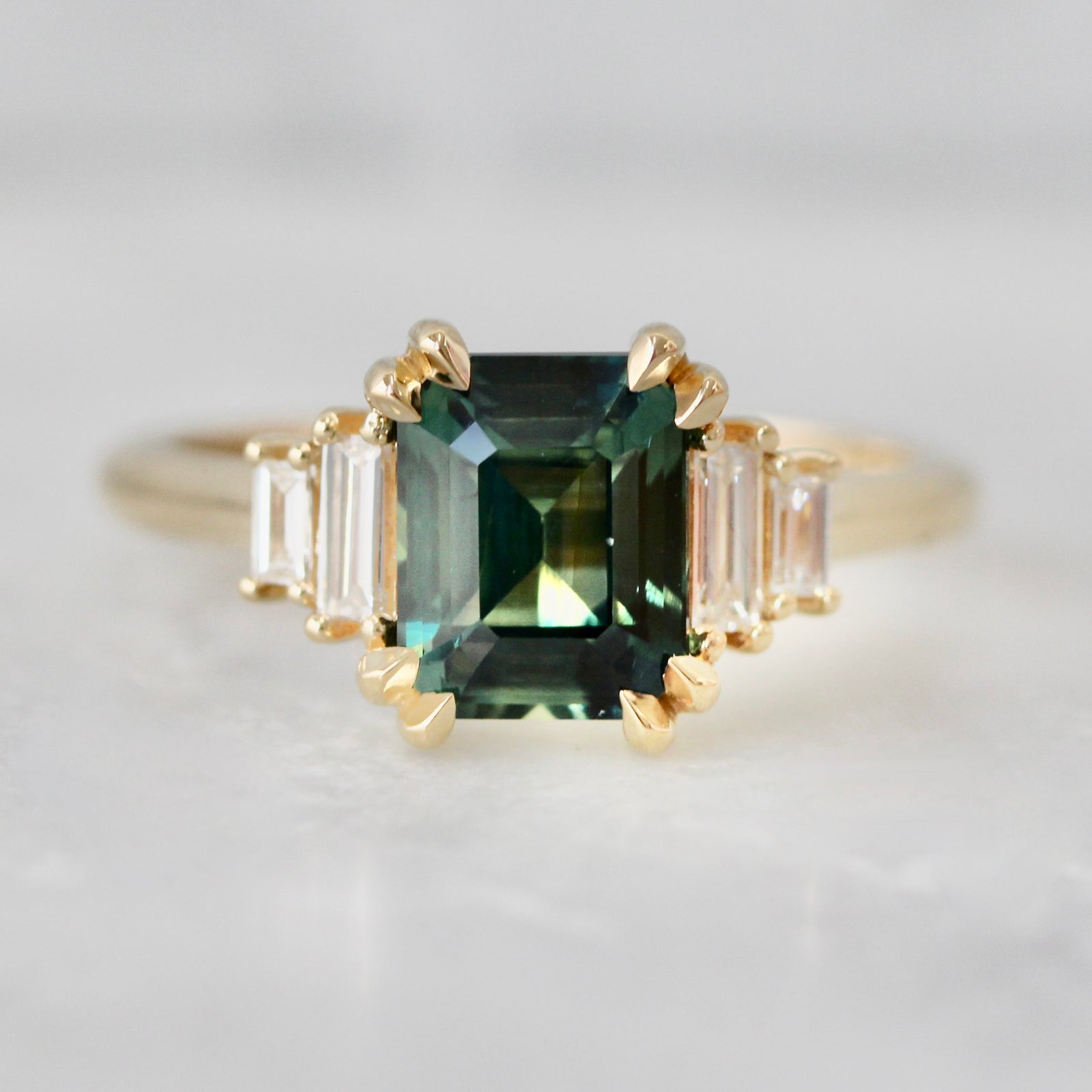 Custom engagement ring with emerald cut green sapphire and baguette diamond side stones by Gem Breakfast