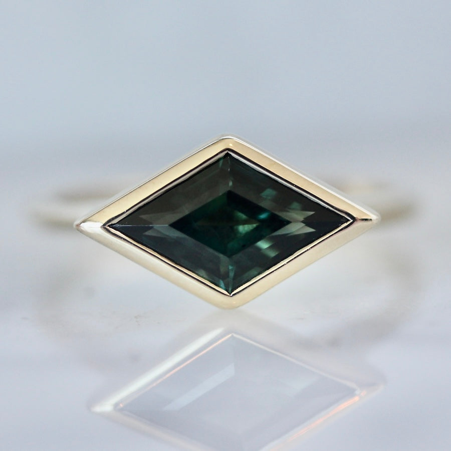 Custom engagement ring with kite cut rich green sapphire in a yellow gold bezel setting by Gem Breakfast