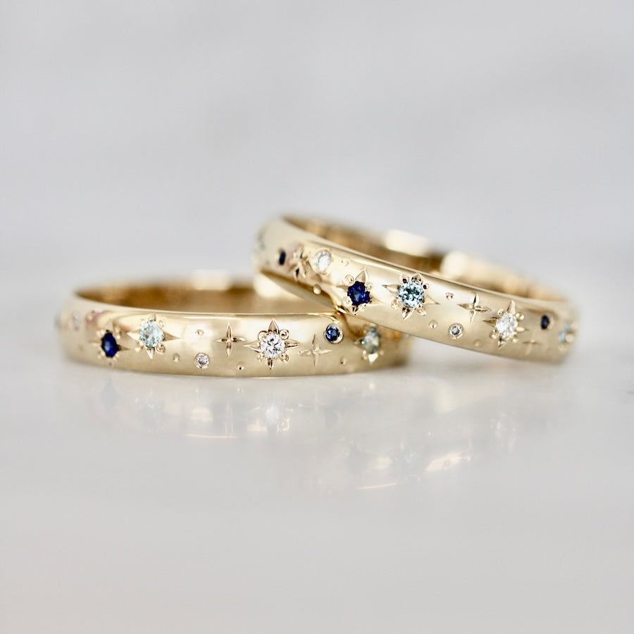 Matching 14k yellow gold wedding bands with hand-engraved stars and star-set diamonds and blue sapphires by Gem Breakfast