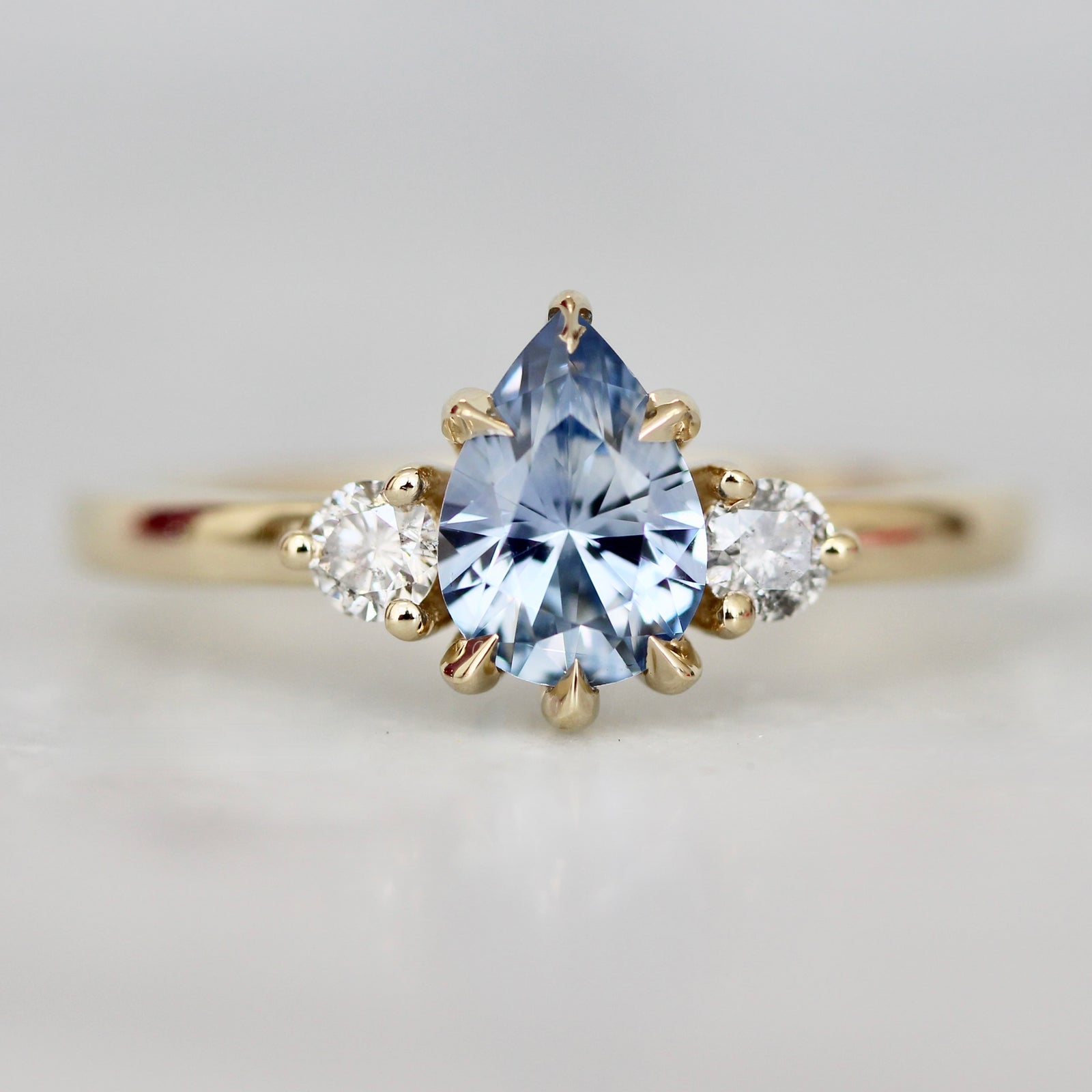 Custom engagement ring with pear cut periwinkle blue sapphire and round brilliant diamond side stones by Gem Breakfast