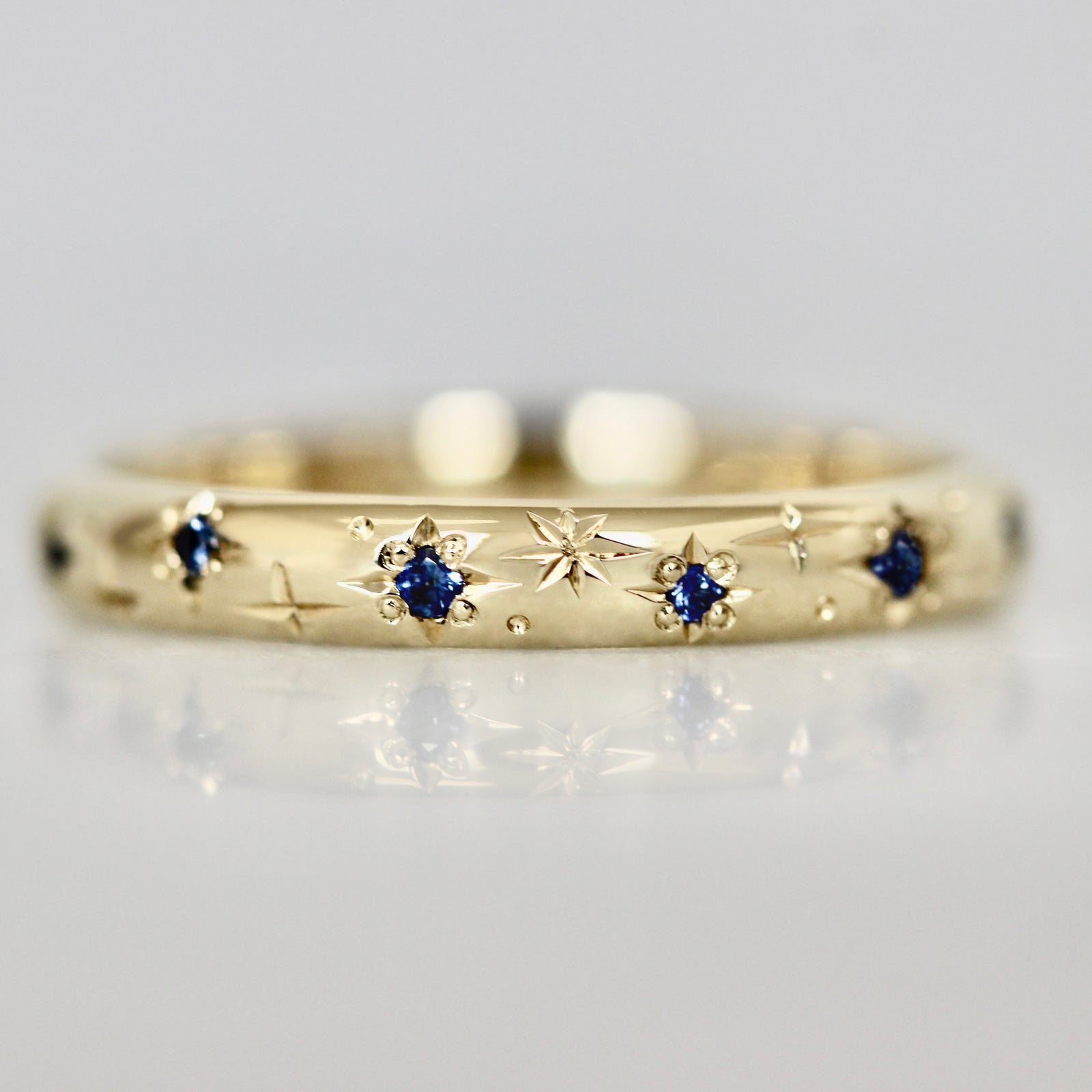 14k yellow gold custom wedding ring with starry hand-engraving and star-set blue sapphires by Gem Breakfast