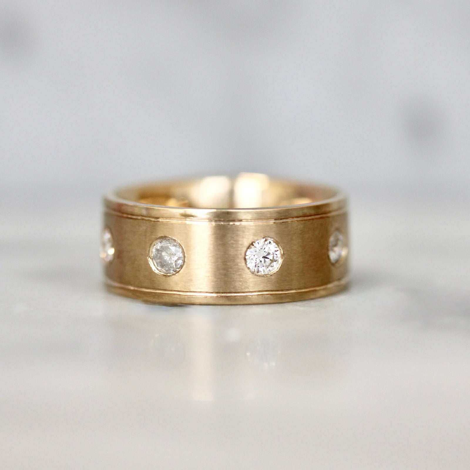 Thick peach gold men’s wedding band with flush-set round brilliant diamonds by Gem Breakfast