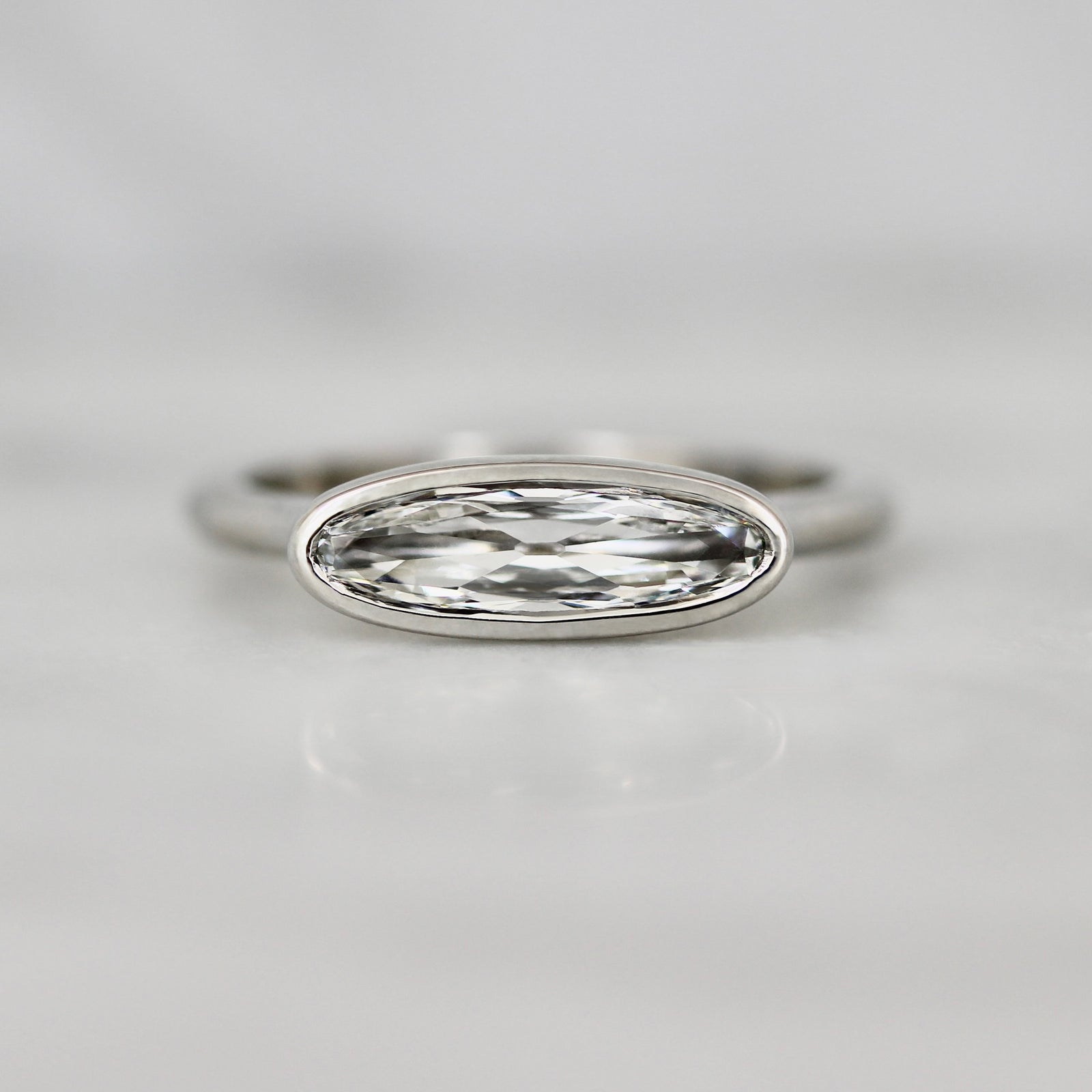 East-west moval diamond custom engagement ring in a platinum bezel setting by Gem Breakfast