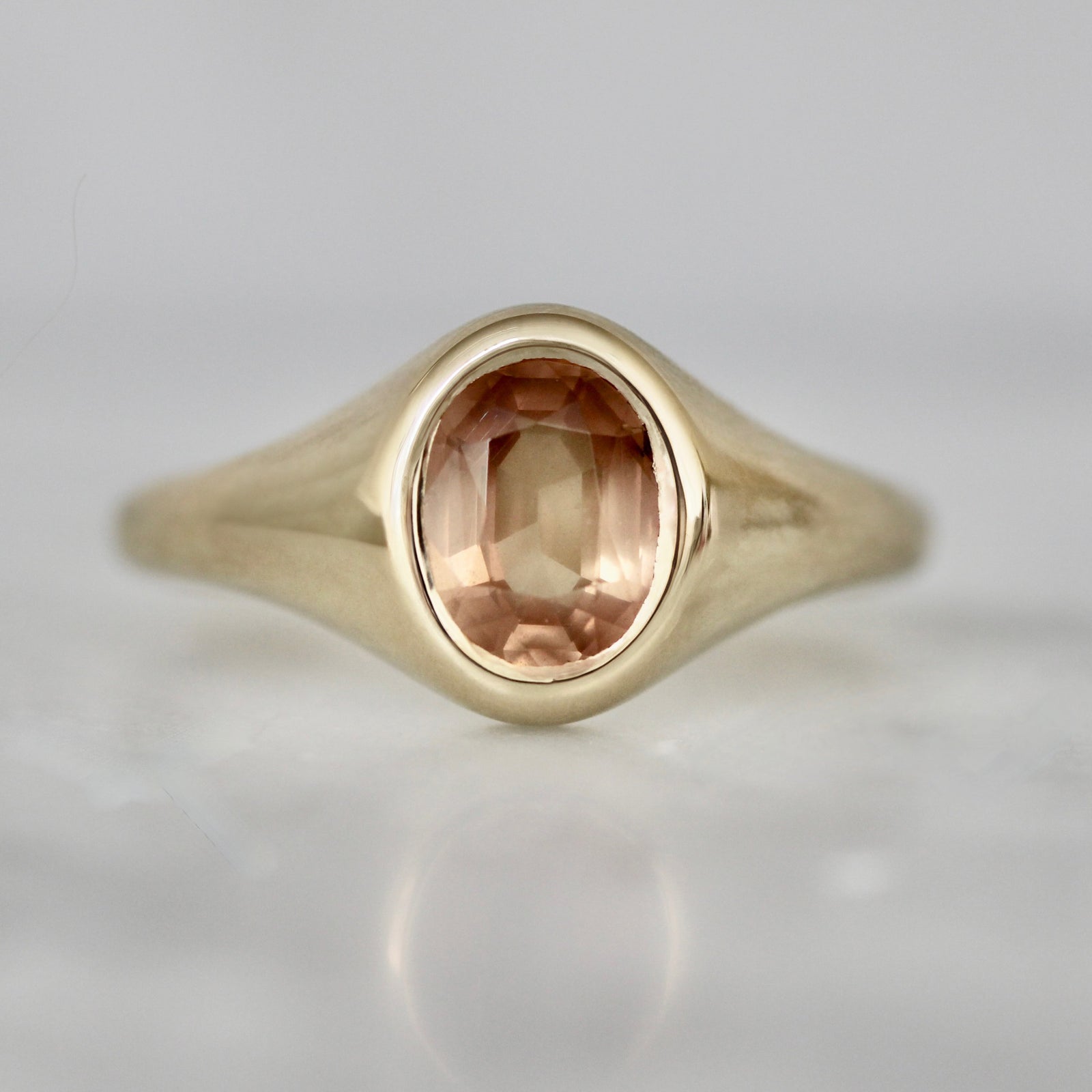 Oval peach sapphire custom signet ring in 14k yellow gold, crafted by Gem Breakfast