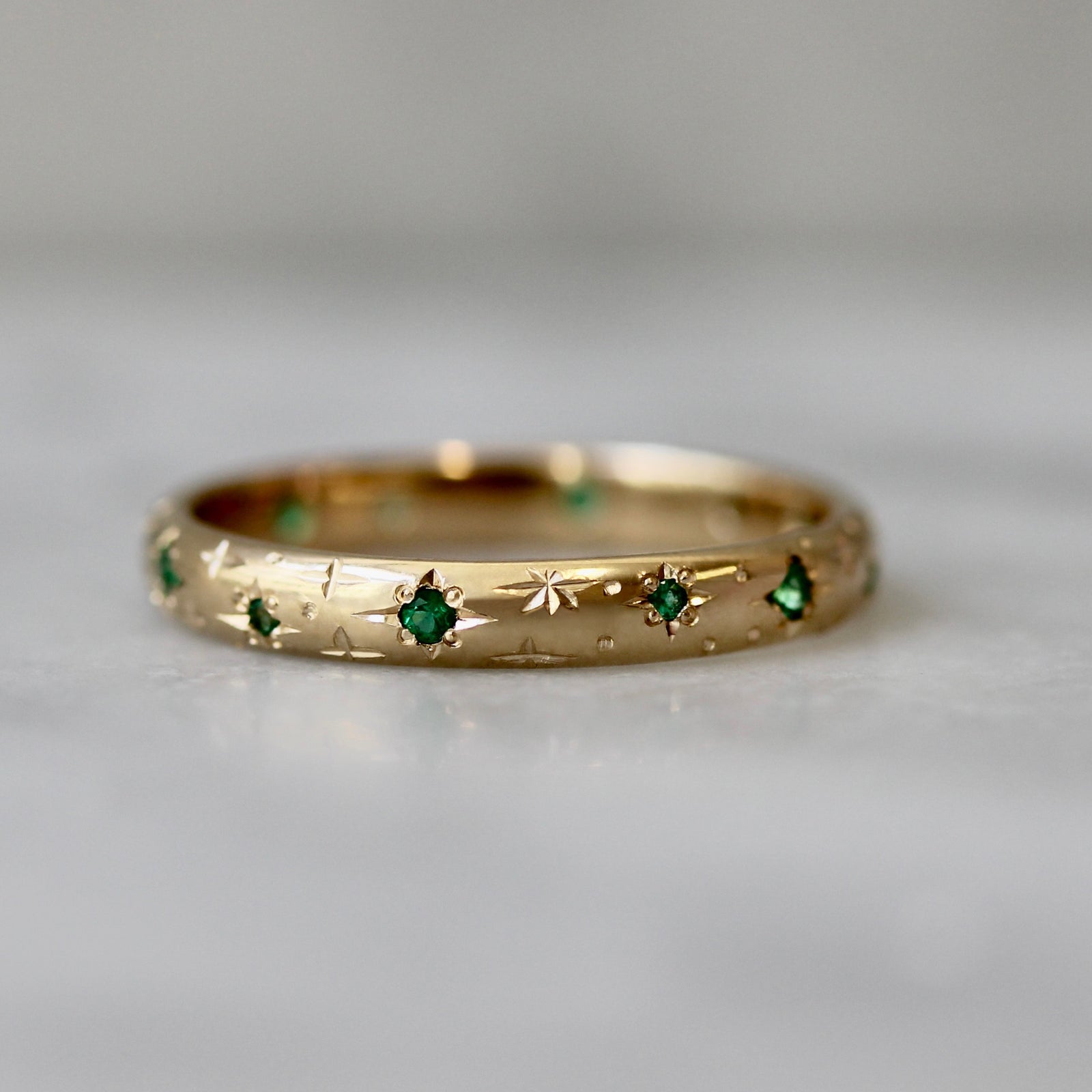 Emerald wedding band in 14k yellow gold with hand-engraved stars and star-set emeralds by Gem Breakfast