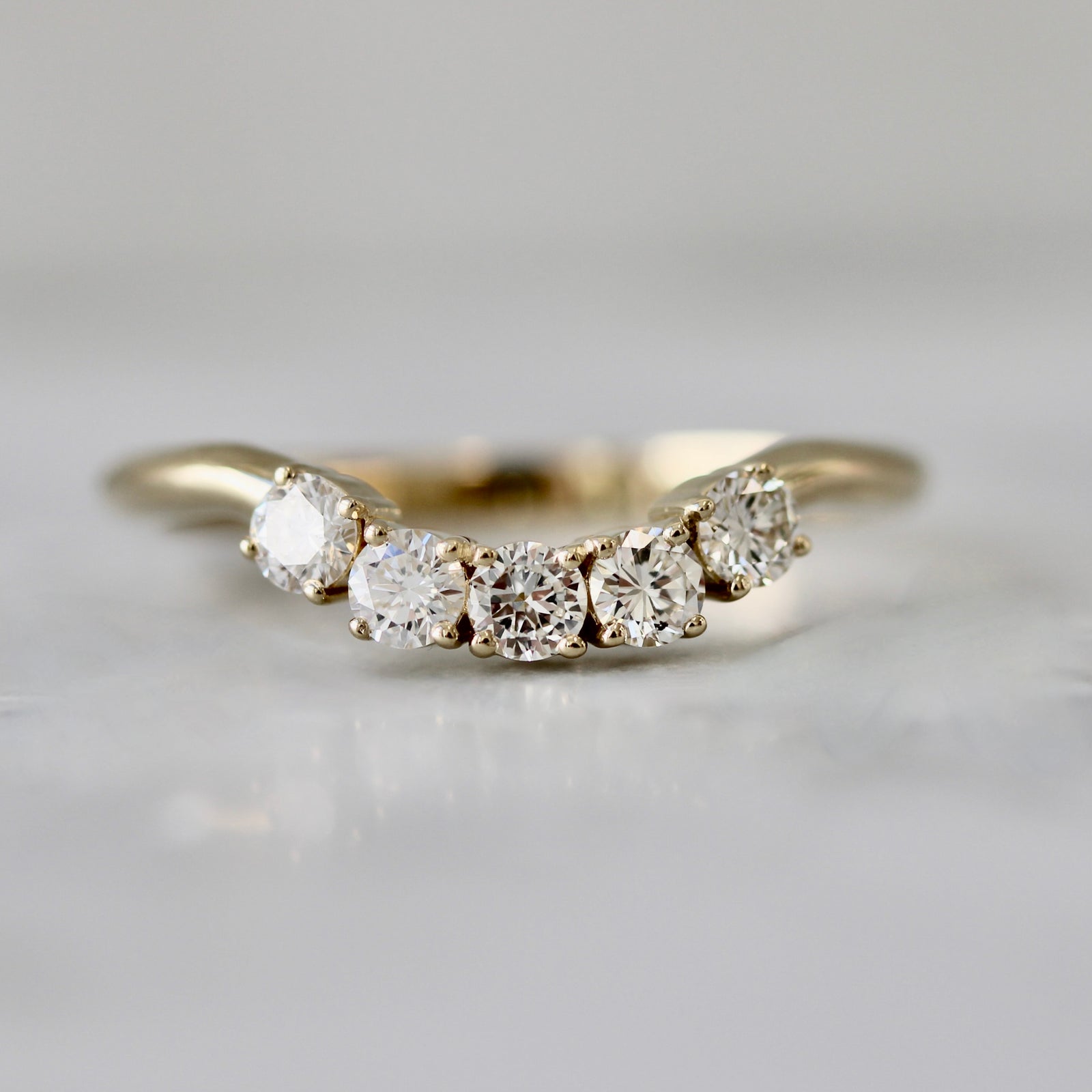 Curved five-stone wedding band with round brilliant white diamonds in 18k yellow gold, custom made by Gem Breakfast