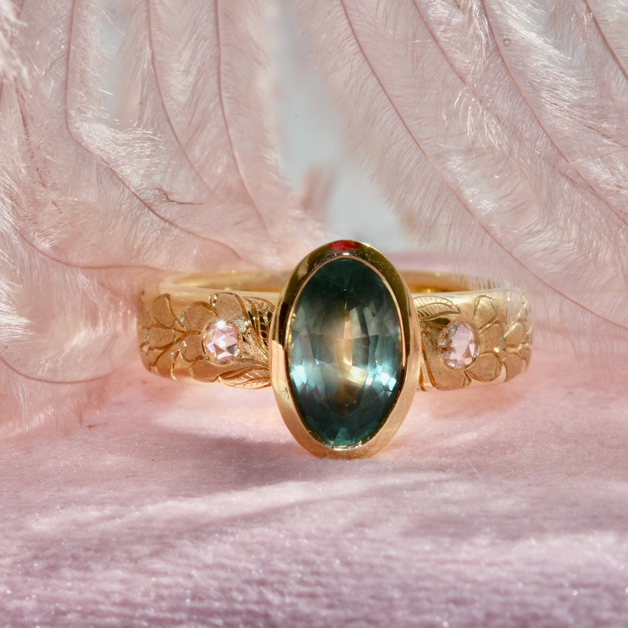 Gold ring with a green gemstone on a engraved band