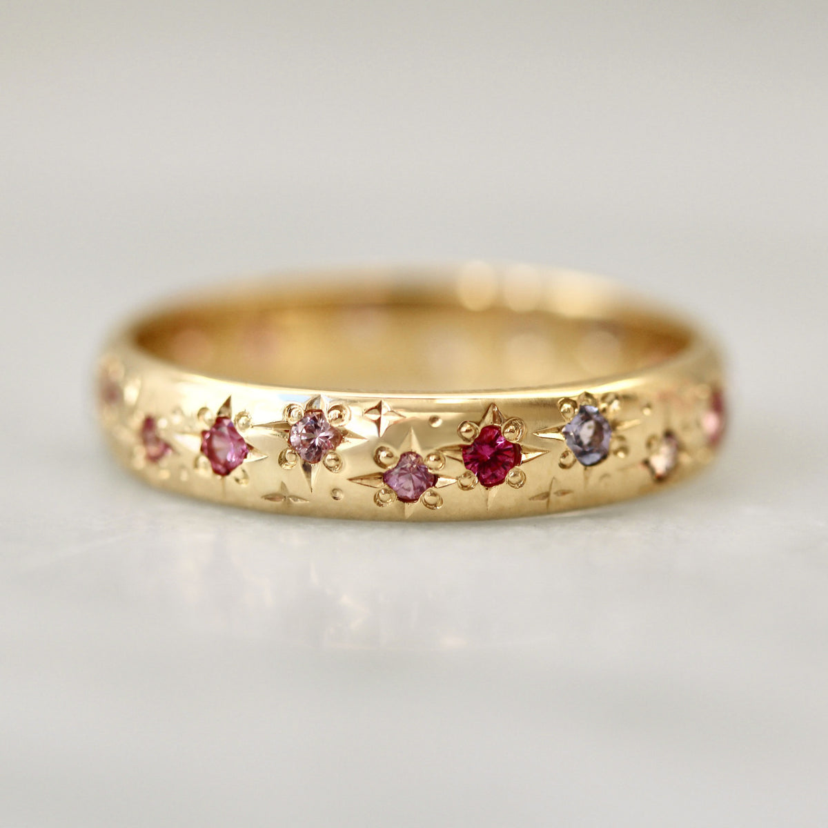 
            Gold ring with embedded gemstones on a light gray background