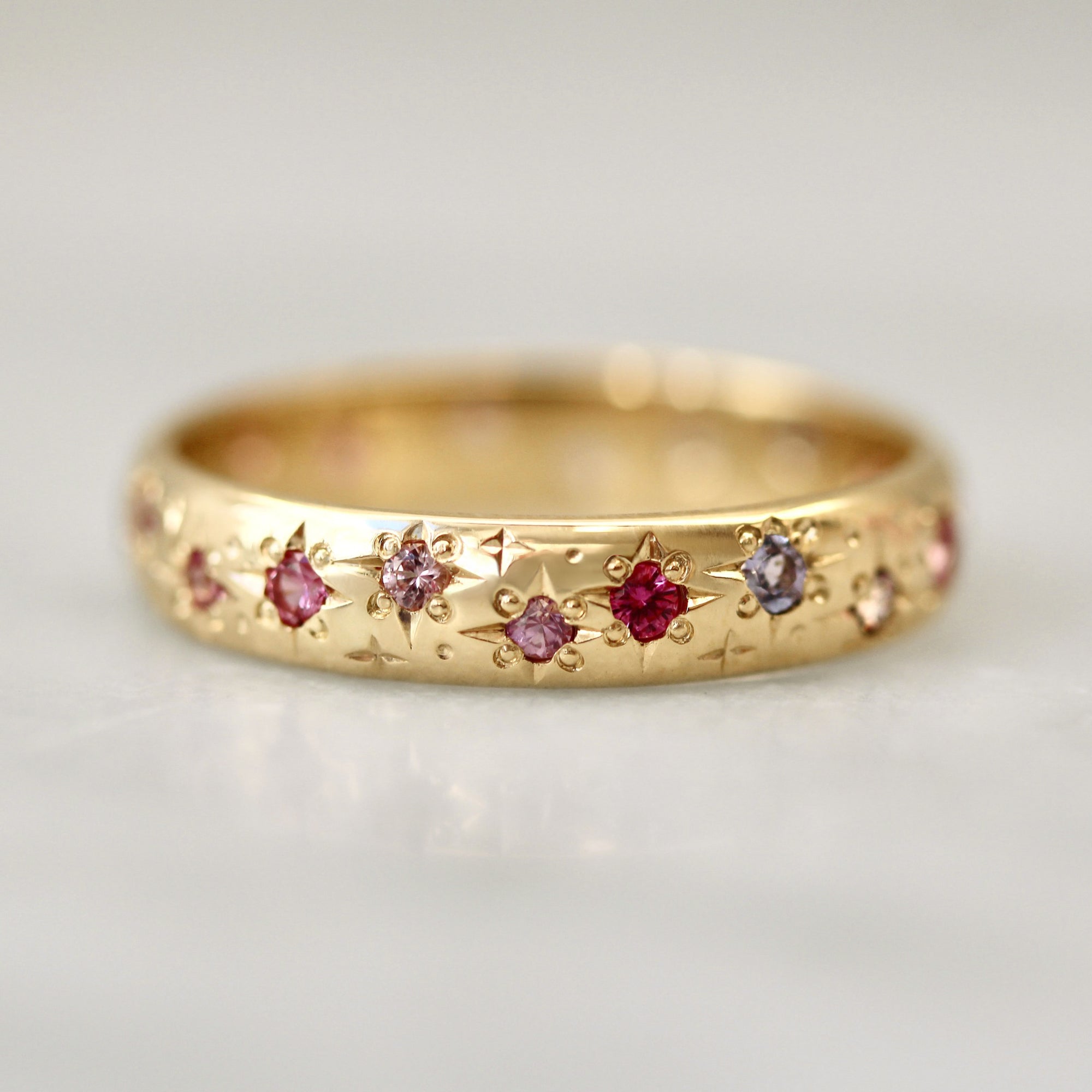 Gold ring with embedded gemstones on a light gray background
