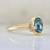 blue oval cut sapphire ring in half bezel with white baguette half halo in yellow gold