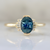 blue oval cut sapphire ring in half bezel with white baguette half halo in yellow gold